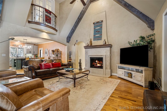 6323 E 111th Pl, Tulsa, OK 74137 - living room with high vaulted ceiling, light wood-style floors, a ceiling fan, a chandelier, and a premium fireplace