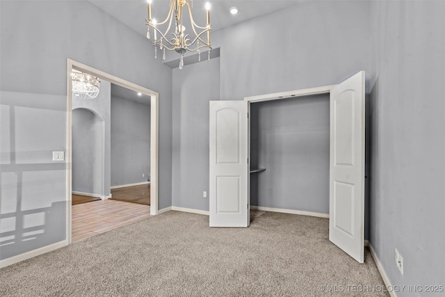 3316 W Jackson St, Broken Arrow, OK 74012 - unfurnished bedroom with baseboards, arched walkways, a high ceiling, a chandelier, and carpet flooring