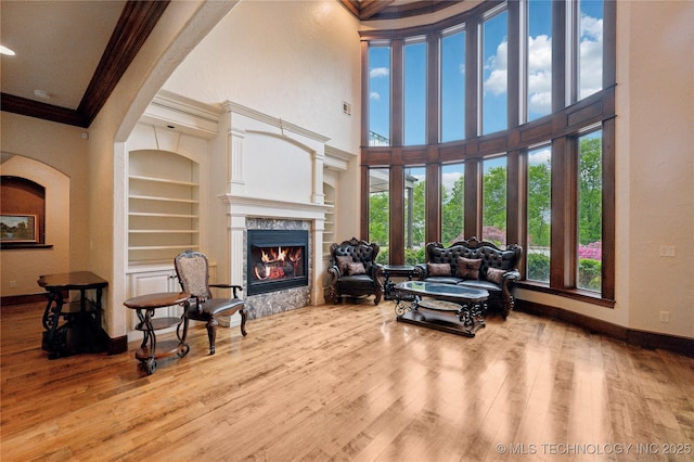 living room featuring crown molding, baseboards, wood finished floors, and a premium fireplace