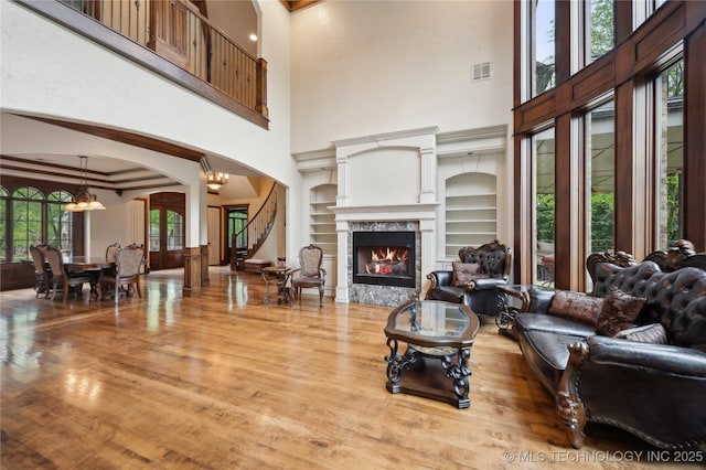 living room with visible vents, built in features, arched walkways, wood finished floors, and a high ceiling