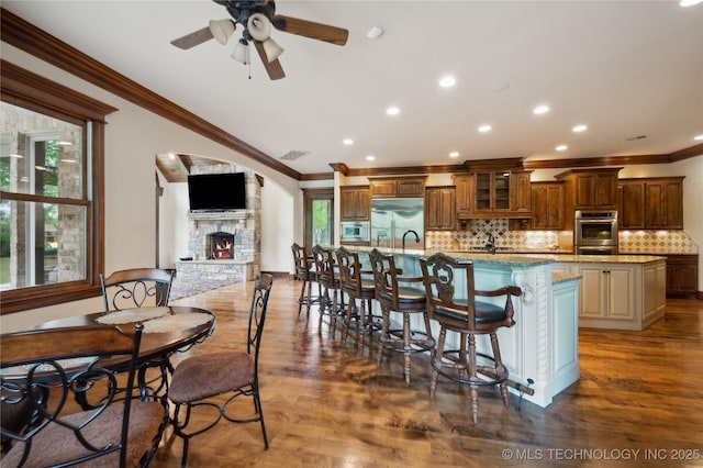 kitchen featuring a large island, ornamental molding, ceiling fan, and a fireplace