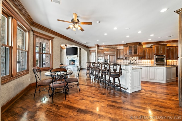 9931 N Chadford Rd, Owasso, OK 74055 - dining space featuring ornamental molding, a ceiling fan, dark wood-style floors, recessed lighting, and arched walkways