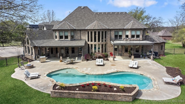 rear view of property with a yard, a patio, a fenced backyard, and a balcony