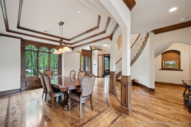 dining area with crown molding, arched walkways, visible vents, and light wood-type flooring