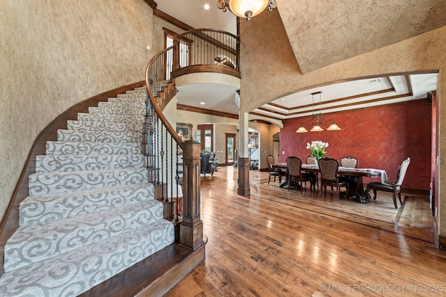 9931 N Chadford Rd, Owasso, OK 74055 - stairs with arched walkways, crown molding, a high ceiling, hardwood / wood-style flooring, and a textured wall