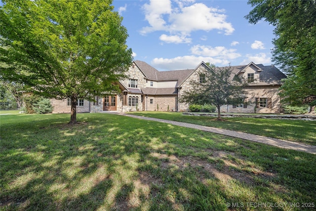 tudor home featuring a front yard and stone siding