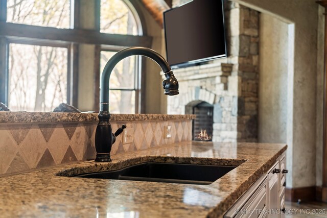 9931 N Chadford Rd, Owasso, OK 74055 - kitchen with light stone countertops, a fireplace, and backsplash