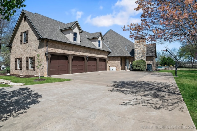 9931 N Chadford Rd, Owasso, OK 74055 - view of side of property with concrete driveway, brick siding, roof with shingles, and a chimney