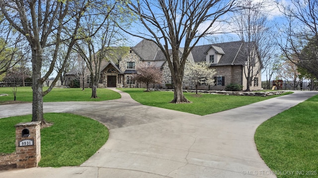 9931 N Chadford Rd, Owasso, OK 74055 - view of front of house featuring stone siding, a front yard, brick siding, and curved driveway