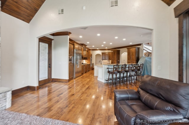 9931 N Chadford Rd, Owasso, OK 74055 - living area with arched walkways, light wood-style flooring, ornate columns, vaulted ceiling, and recessed lighting