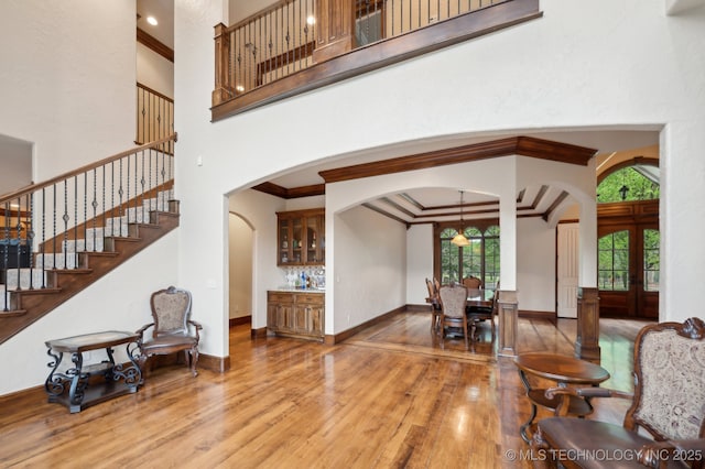 9931 N Chadford Rd, Owasso, OK 74055 - entrance foyer with arched walkways, wood finished floors, a high ceiling, ornamental molding, and stairway