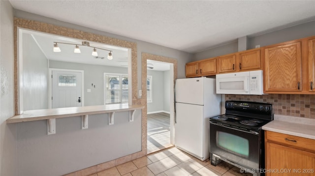 345 N Pine, Dewey, OK 74029 - kitchen featuring white appliances, track lighting, light countertops, backsplash, and a kitchen bar