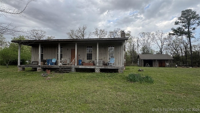 24252 S Independence Rd, Heavener, OK 74937 - back of property with a chimney, board and batten siding, an outdoor structure, a porch, and a yard
