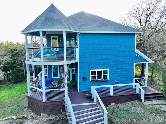 rear view of house featuring a balcony, a shingled roof, and a deck