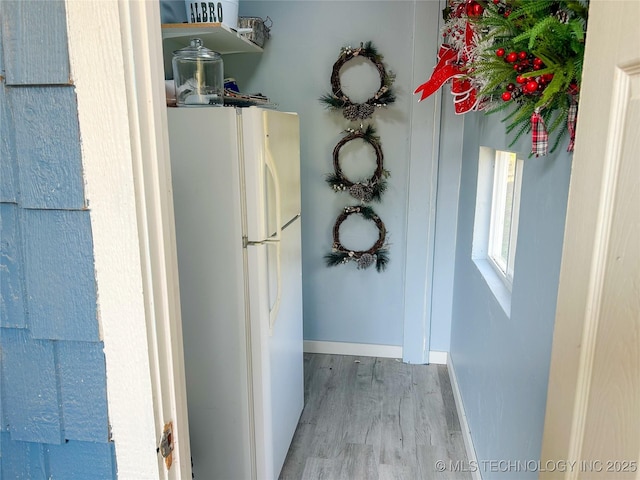 interior space with freestanding refrigerator, baseboards, and wood finished floors