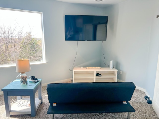 living area with baseboards, visible vents, and carpet