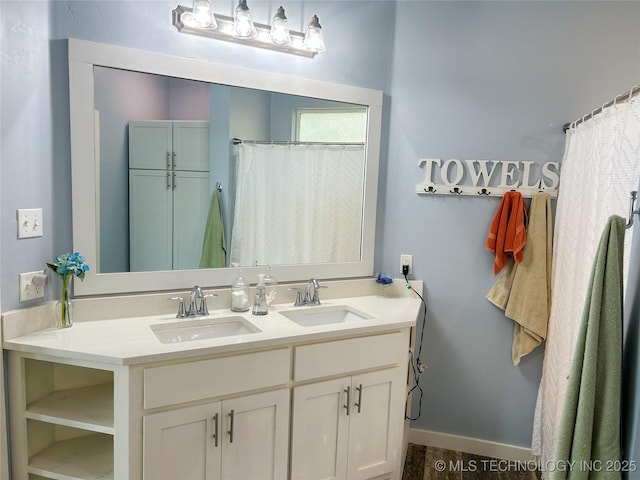 full bathroom with baseboards, double vanity, and a sink