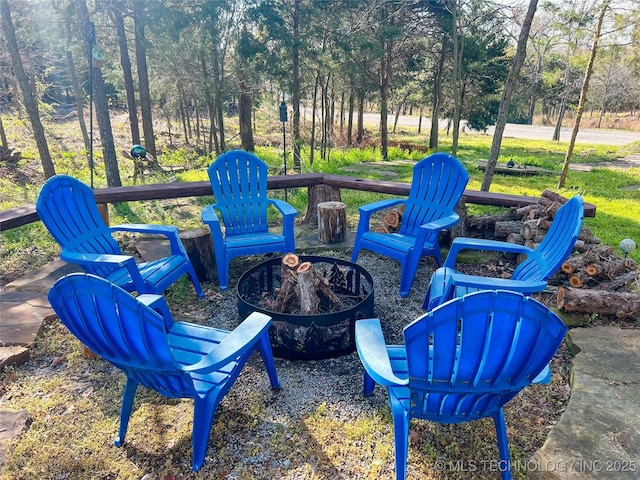 view of yard featuring a wooded view and an outdoor fire pit