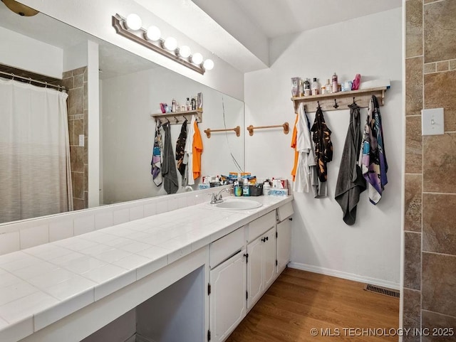 511 Tandy Walker, Silo, OK 74701 - bathroom with vanity, baseboards, tiled shower, visible vents, and wood finished floors