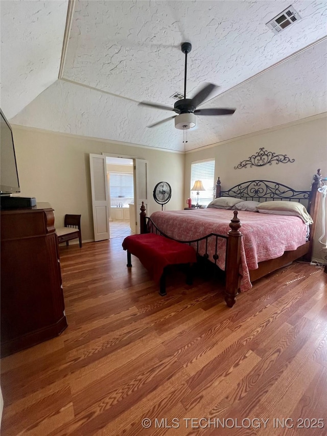 bedroom with a ceiling fan, visible vents, light wood finished floors, and a textured ceiling