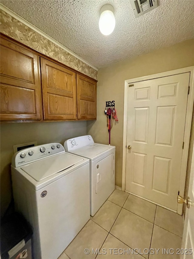 laundry area with light tile patterned flooring, a textured ceiling, visible vents, washer and dryer, and cabinet space