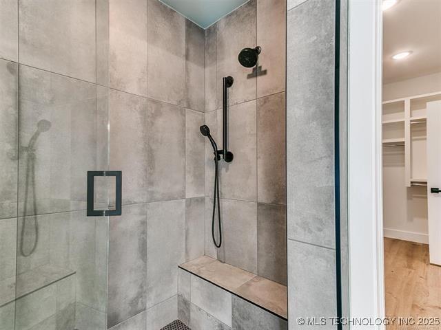 bathroom featuring a shower stall, wood finished floors, and a walk in closet