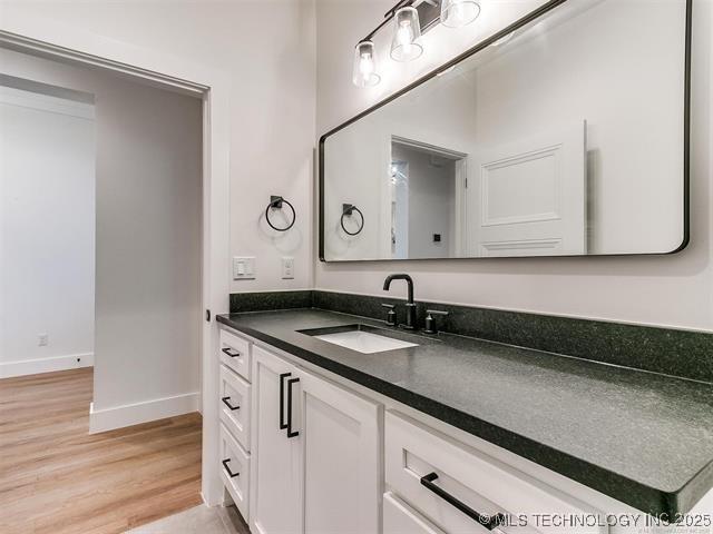 bathroom featuring wood finished floors, vanity, and baseboards