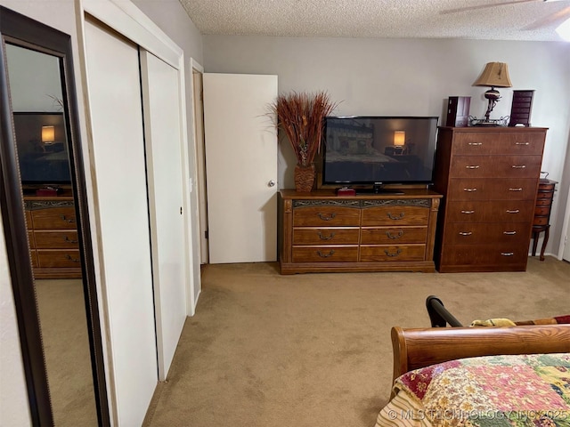 bedroom with light colored carpet, a closet, and a textured ceiling