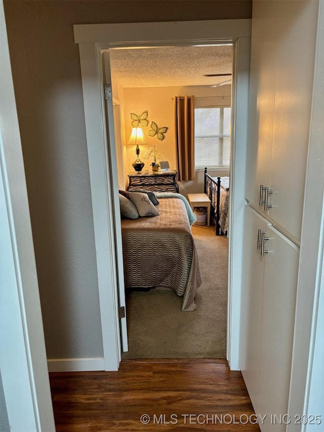 carpeted bedroom with baseboards, a textured ceiling, and wood finished floors