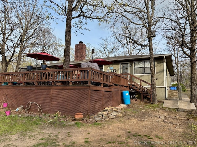 back of house featuring a wooden deck, a gate, stairs, and a chimney