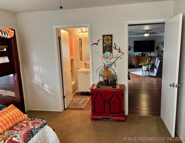 carpeted bedroom with a sink, connected bathroom, and a textured ceiling