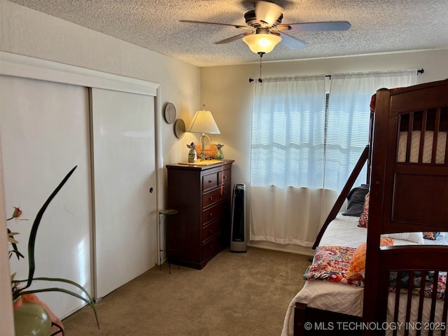 carpeted bedroom featuring a closet, ceiling fan, and a textured ceiling