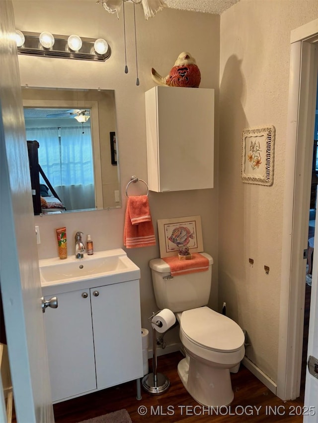 bathroom featuring toilet, vanity, baseboards, and wood finished floors