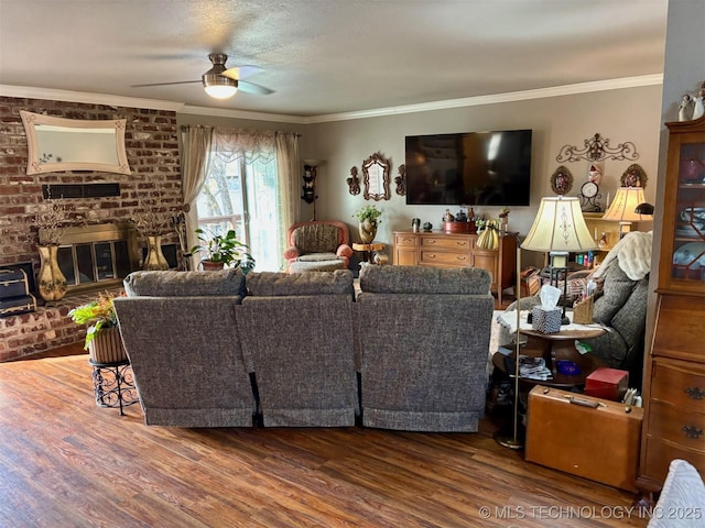 living area with a ceiling fan, crown molding, a fireplace, and wood finished floors