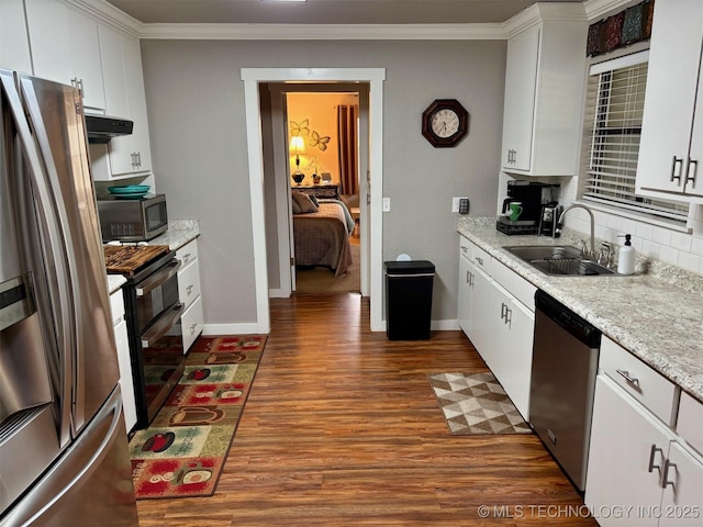 kitchen featuring crown molding, stainless steel appliances, dark wood finished floors, a sink, and white cabinets