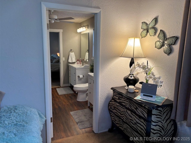 ensuite bathroom with toilet, vanity, wood finished floors, a textured ceiling, and ceiling fan
