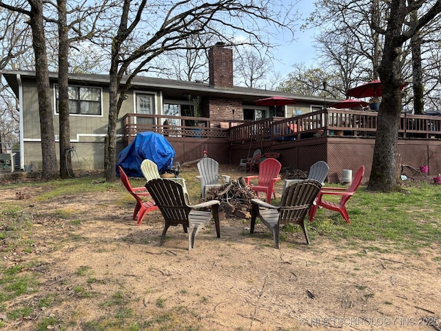 rear view of house featuring a fire pit, a deck, and a chimney