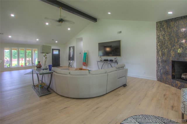 living area with wood finished floors, a fireplace, lofted ceiling with beams, baseboards, and ceiling fan