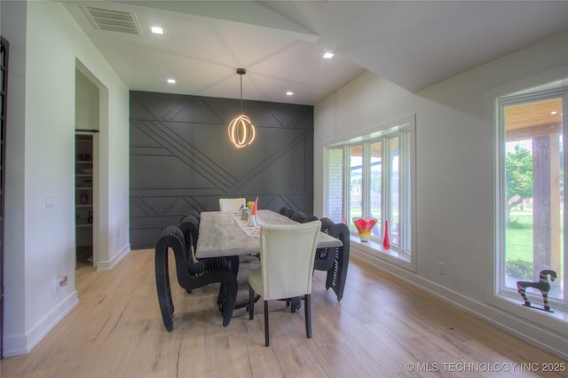 dining space featuring baseboards, light wood-style floors, a decorative wall, and visible vents