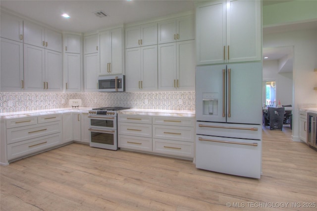 kitchen featuring white appliances, recessed lighting, light wood finished floors, backsplash, and light countertops