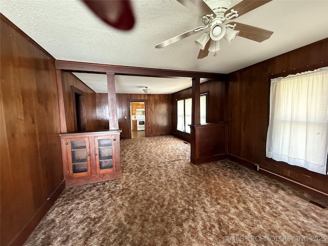 609 N E St, Mcalester, OK 74501 - unfurnished living room featuring carpet, a textured ceiling, wooden walls, and ceiling fan