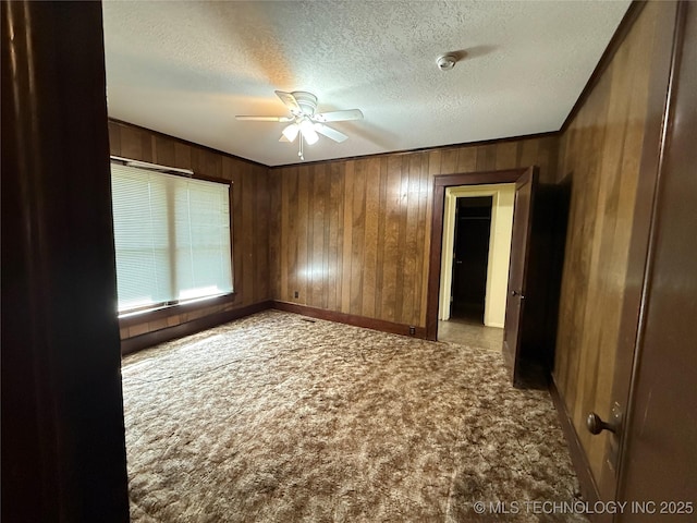 609 N E St, Mcalester, OK 74501 - carpeted spare room with wood walls, a textured ceiling, and ceiling fan