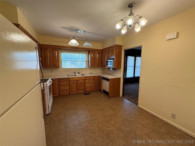 609 N E St, Mcalester, OK 74501 - kitchen with an inviting chandelier, white appliances, a sink, light countertops, and baseboards