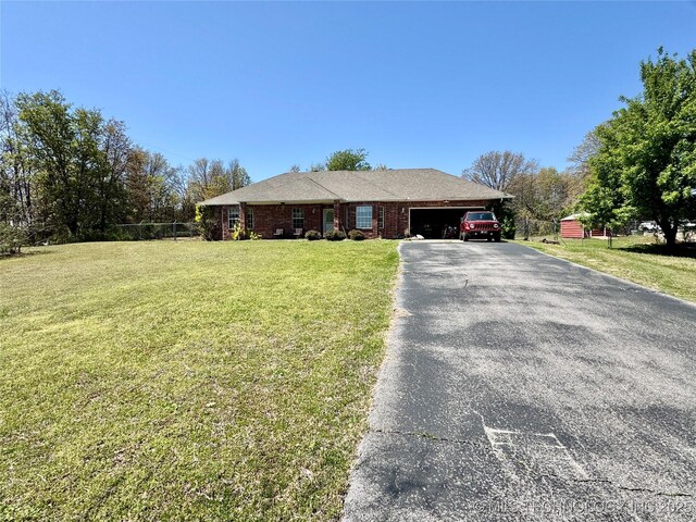 ranch-style house featuring an attached garage, fence, brick siding, a front lawn, and driveway