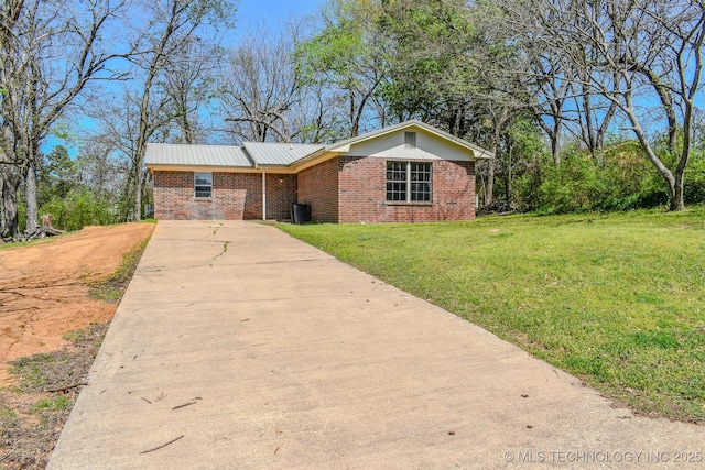 ranch-style house with brick siding, concrete driveway, metal roof, and a front lawn
