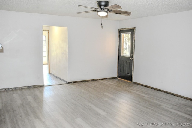 unfurnished room featuring a textured ceiling, baseboards, ceiling fan, and wood finished floors