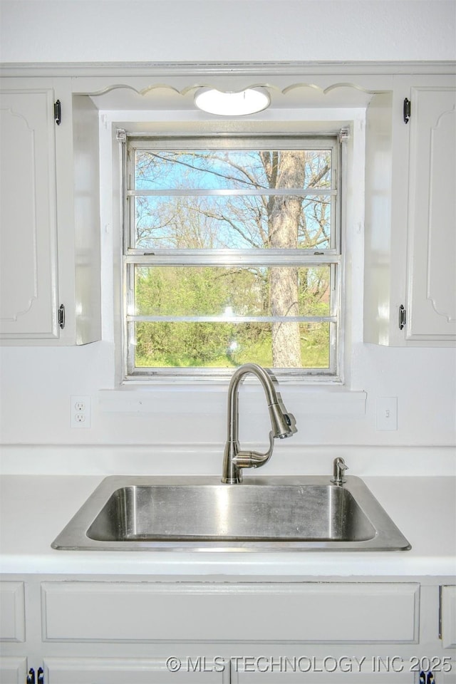 interior details featuring white cabinetry, a sink, and light countertops