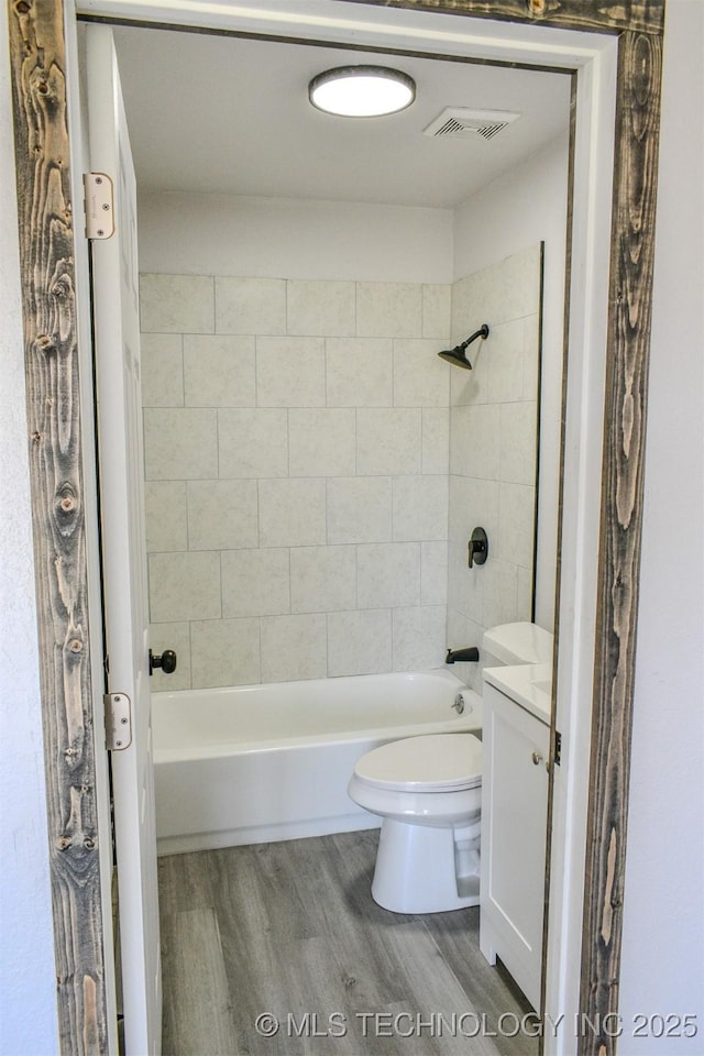 bathroom featuring vanity, shower / bath combination, toilet, visible vents, and wood finished floors