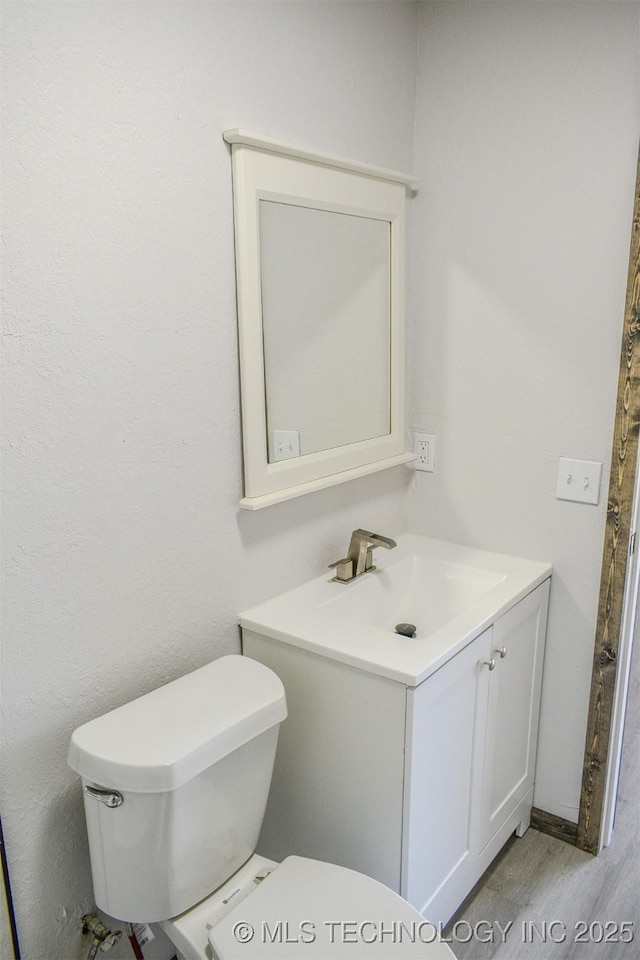 bathroom with toilet, vanity, and wood finished floors