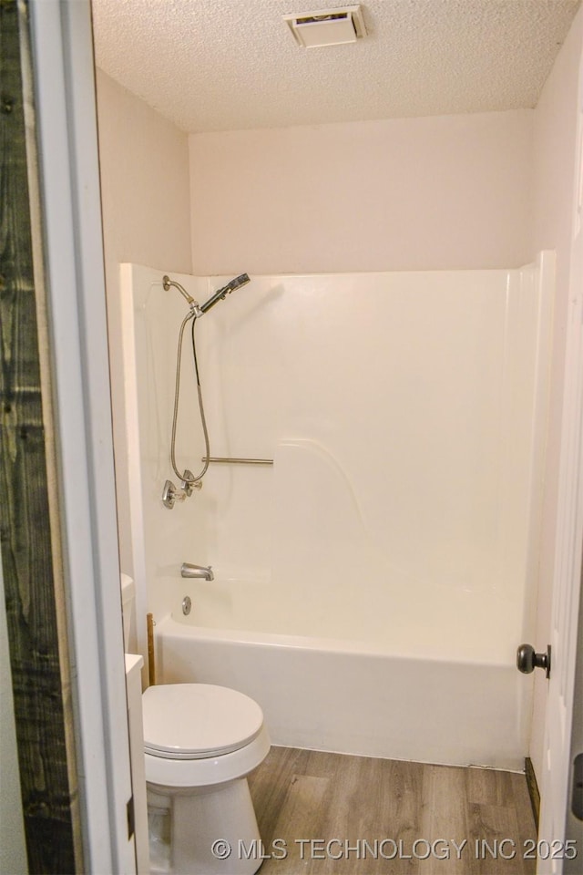 bathroom with toilet, visible vents, wood finished floors, and a textured ceiling